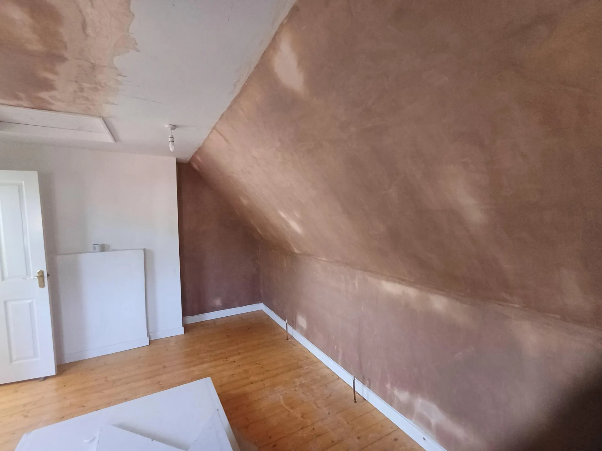 Loft room with a smooth pink plaster skim finish and wood floor